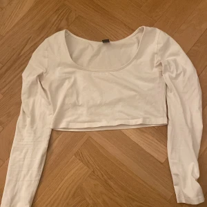 Vit croppad topp från Shein - Säljer en stilren vit croppad topp från Shein. Toppen har långa ärmar och en rundad halsringning, perfekt för en trendig look. Passar bra till både jeans och kjol. Perfekt för vår och sommar!