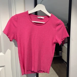 Rosa ribbad topp från ONLY - Säljer en snygg rosa ribbad topp från ONLY. Den har korta ärmar och en rund halsringning. Perfekt för en avslappnad stil med en touch av färg.
