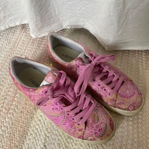 Rosa sneakers med paisley mönster - Snygga rosa sneakers från H&M med ett unikt blommigt mönster i guld och rosa. Skorna har snörning och en bekväm passform. Perfekta för att ge en färgglad touch till din outfit. Storlek 39