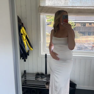 Vit klänning - Säljer en stilren vit klänning med tunna axelband och en elegant draperad framsida. Klänningen har en dragkedja i ryggen och är tillverkad i ett mjukt material som ger en fin passform. Perfekt för sommarens alla tillfällen!