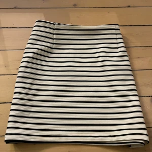 Randig kjol från Vero Moda - Snygg randig kjol från Vero Moda i svart och vit med dragkedja bak. Perfekt för en stilren look. Kjolen har en klassisk passform och är enkel att matcha med olika toppar. Storlek 38 men passar även 36 bra. Aldrig använd. Pris kan diskuteras!🥰❤️