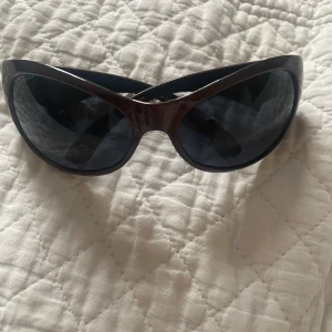 Bruna solglasögon med kattögonform - Snygga bruna solglasögon i kattögonform med mörka linser. Perfekta för en stilren look. De har en cool design som passar till många olika outfits.