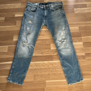 Blå jeans från Replay - Säljer ett par blå Replay Anbass jeans med slitna detaljer och är slim fit. Aldrig andvända.