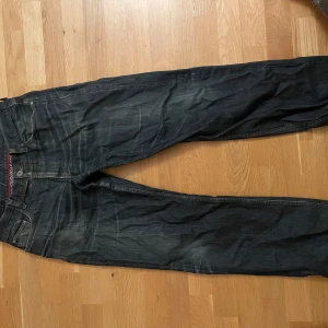 Mörkblå jeans från Tommy Hilfiger - Snygga mörkblå jeans från Tommy Hilfiger med klassisk femficksdesign. Jeansen har en diskret logga på den lilla fickan och en röd detalj vid linningen. Perfekta för en stilren look. Storlek W33L34