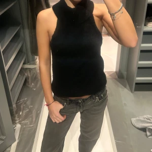 Svart ärmlös polotopp - Säljer en stilren svart ärmlös polotopp. Perfekt för lager-på-lager eller att bära som den är. Toppens enkla design gör den lätt att matcha med olika outfits.