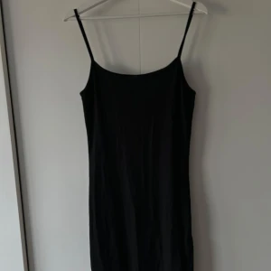 Svart ribbad klänning - Snygg svart ribbad klänning med smala axelband och enkel design. Perfekt för en stilren look. Klänningen har en rak passform samt slits och är tillverkad i ett mjukt material. Oanvänd ✨🌟