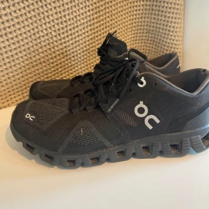 On cloud X skor - Säljer ett par svarta sneakers från On med deras unika CloudTec-sula för extra komfort. Skorna har snörning och är perfekta för både träning och vardag. Tillverkade med schweizisk ingenjörskonst för optimal prestanda.