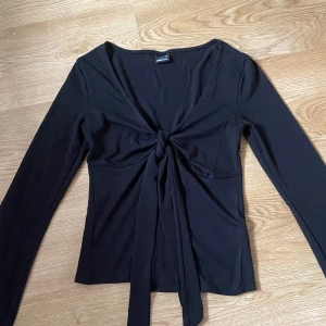 svart långärmad topp (gina tricot) - snygg svart långärmad topp från gina tricot med knytning framtill!🖤nyköpt o endast använd en gång, passade inte riktigt min stil🫶🏻 absolut inget fel på plagget