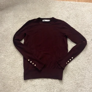 Vinröd finstickad tröja från Zara - Vinröd finstickad tröja från Zara med långa ärmar och guldiga knappar på ärmarna.