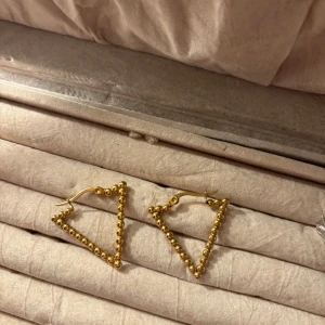 Guldiga triangelformade örhängen - Snygga guldiga örhängen i form av trianglar, gjorda av små kulor som ger en unik och modern look. Perfekta för att ge en stilren touch till din outfit. Säljer då de aldrig har används😊