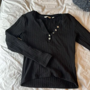 Svart ribbad tröja från Awake - Säljer en svart ribbad tröja från Aware med knappar framtill. Tröjan har en v-ringad design och långa ärmar, perfekt för söt outfit. Passar bra till både jeans/kostymbyxor och kjol. Använd fåtal gånger, hör av dig vid intresse!💕
