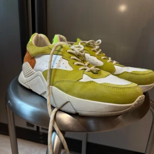 Gröna sneakers med mockadetaljer - Snygga sneakers i en mix av grönt, vitt och brunt med mockadetaljer. Skorna har en modern design med snörning och en bekväm sula. 