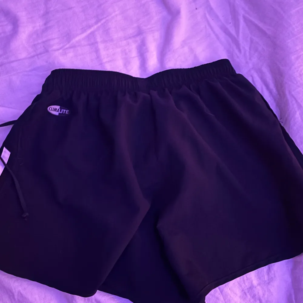 Säljer ett par svarta träningsshorts från Adidas i storlek XS. De har de klassiska tre vita ränderna på sidorna och en elastisk midja för bästa passform. . Shorts.