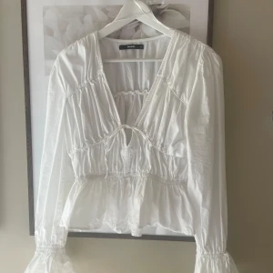 Vit Blus - Blus från BikBok, bara använd en gång❤️ Knyten fram samt nere vid armarna. Super söt men kommer aldrig till användning 🥰 Nypris 499:- Sista bilden är tagen från Bikbok 