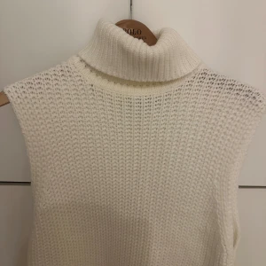 Vit stickad ärmlös polotröja - Säljer en superfin vit stickad poloväst. Perfekt för lager-på-lager under höst och vinter. Den har en mysig polokrage och är i ett mjukt material. Passar både till vardags och lite finare tillfällen.