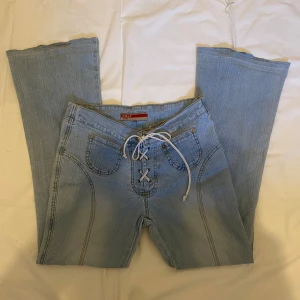 Snörade jeans - Ett par lågmidjade ljusblåa bootcut jeans med snörning i midjan. De är ca 40 cm i midjemått om det möta tvärs över och ca 74 cm i innerbenslängd. Det är bara och höra av sig om du har frågor eller vill ha flera bilder💕