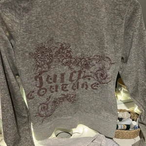 Grå hoodie från Juicy Couture - Säljer en grå hoodie från Juicy Couture SOM JAG ÄLSKARR ( men har växt ur🥲) med dragkedja och ett snyggt mönster på ryggen. Tröjan har långa ärmar och en bekväm passform. Perfekt för en avslappnad stil. Hör av dig vid intresse! VINTAGE TILLVERKAS INTE LÄNGRE 🤗❤️Den är i M men passar mer xs och s