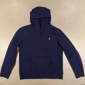 Ralph Lauren Hoddie - Säljer en snygg mörkblå hoodie från Polo Ralph Lauren med det klassiska broderade logotypen på bröstet. Perfekt för en avslappnad stil. Mycket bra skick, använd fåtal gånger. Det är storlek XL i barn från kidsbrandstore. Men den passar S eller Xs i herr.
