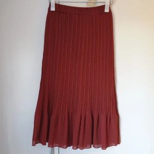 Kjol - Snygg röd plisserad kjol. faller vackert ner till knälängd. Den är i storlek xs och är bara använd ett fåtal gånger