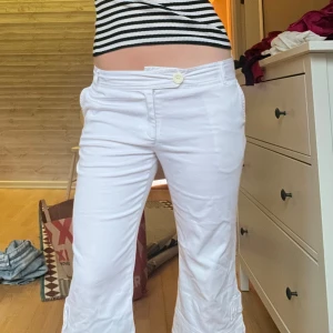 Vita capribyxor - Snygga vita capribyxor med knapp och dragkedja framtill. De har en avslappnad passform och är perfekta för varmare väder. Byxorna har fickor både fram och bak, vilket ger en praktisk touch.