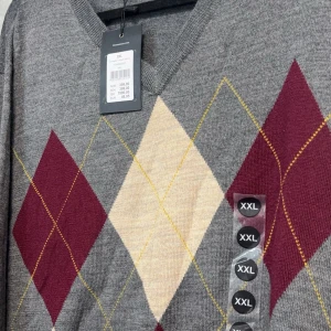 Grå tröja med argyle-mönster från Dressmann - Snygg grå tröja från Dressmann med klassiskt argyle-mönster, beige och gult. Tröjan har en v-ringad hals och långa ärmar, perfekt för en stilren look.