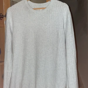 (NYSKICK) Grå ribbad tröja från These Glory Days - Säljer en stilren grå ribbad tröja från These Glory Days. Tröjan har en klassisk rund hals och långa ärmar, perfekt för en minimalistisk look.  Nypris ligger på ca 800