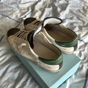 Philippe model - Snygga vita sneakers från Philippe Model med gröna och svarta detaljer. Skorna har snörning och en robust sula med märkets namn. Perfekta för en avslappnad stil. Nypris 3800 mitt pris 1499 Skick 7/10 box fås med. Kan tänka mig byta mot lanvins storlek 47/ uk 12. Priset är inte hugget i sten!