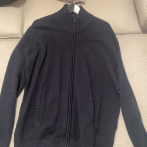 Overshirt  - Säljer en stilren svart kofta med dragkedja och ribbade detaljer vid krage och fickor. Perfekt för kyligare dagar och enkel att matcha med olika outfits. Storlek L men passar M använd 2-3 ggr. 500kr nypris 