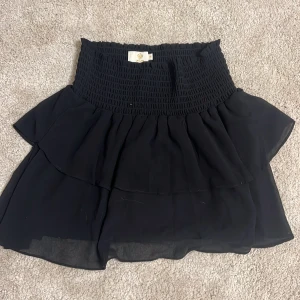 Svart kjol från Made by Chelsea - Snygg svart kjol med volangdetaljer från Made by Chelsea. Kjolen har en elastisk midja som ger en bekväm passform. Nypris 500 kr