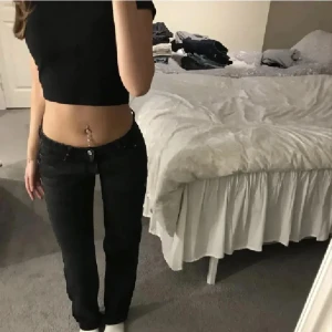 Svarta jeans - Snygga svarta jeansbyxor med låg midja och en tight passform. Perfekta för en stilren look. Byxorna har en klassisk design med knappar och dragkedja framtill. Lågmidjade. I en svart urtvättad färg.