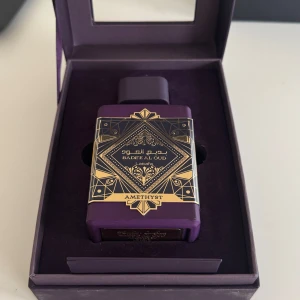 Badee Al Oud Amethyst Parfym - Elegant parfym i en lyxig lila flaska med gulddetaljer. Doften Amethyst ger en känsla av mystik och exklusivitet. Perfekt för den som vill sticka ut med en unik och sofistikerad doft. Den är knappt använd, 100ml