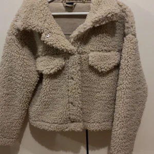  teddyjacka - Mysig beige teddyjacka med knappar framtill och två fickor på bröstet. Använd få gånger 