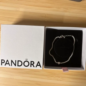 Silverarmband från Pandora - Silverarmband från Pandora med gnistrande stenar och ett hjärtformat smycke i mitten. (Sparkling heart tennisarmband) Armbandet kommer i orginalask. Nypris 999kr.