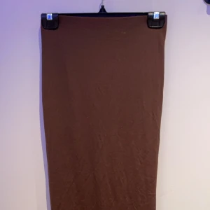 Brun kjol från Zara - Snygg brun kjol från Zara i en enkel och stilren design. Kjolen har en tight passform och är perfekt för en minimalistisk look. Tillverkad i ett mjukt och bekvämt material. Har aldrig haft på mig kjolen den har bara legat i min låda bland kläder och har aldrig kommit till användning!