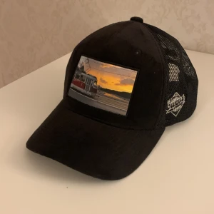 Svart keps med fototryck - Säljer en svart velvet keps med bild av en spårvagn och en solnedgång. Har nästan aldrig använt den och den har inga märken eller hål. 