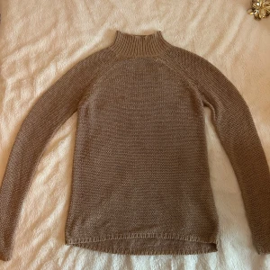 Beige stickad polotröja från Vila - Säljer en stilren beige stickad polotröja från Vila. Tröjan har en hög krage och långa ärmar. Den är mjuk och bekväm, vilket gör den till ett utmärkt val för både vardag och mer avslappnade tillfällen. Storlek S