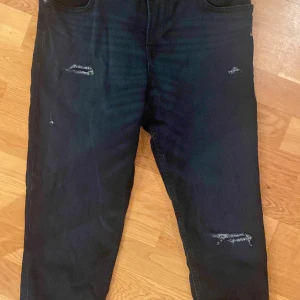 Mörkblå jeans från Jack & Jones - Snygga mörkblå jeans från Jack & Jones med slitna detaljer på framsidan. De har en klassisk femficksdesign och en läderpatch med logotypen på baksidan. Perfekta för en avslappnad stil. Köpte dom för runt 500 kr. Dom är slim fit. Använts 1 gång. Ny tvättade därför är dom lite skrynkliga på bilderna.