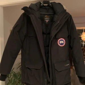 Svart parkajacka från Canada Goose - Säljer en svart parkajacka från Canada Goose med pälsdetaljer på huvan. Jackan har en klassisk design med dragkedja och flera praktiska fickor. Perfekt för kalla vinterdagar. Väldig fin och sparsamt använd.🖤