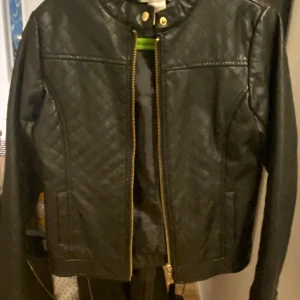 Svart quiltad skinn jacka  - Snygg svart skinn jacka från La Redoute med dragkedja och tryckknapp vid halsen. Säljes i fint skick! 