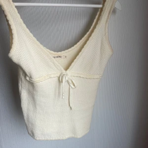 Vit stickad topp från Djerf Avenue - Söt vit stickad topp från Djerf Avenue. Toppen har en v-ringning och knytning framtill, Perfekt för sommaren, använd fåtalet gånger men inga defekter☺️