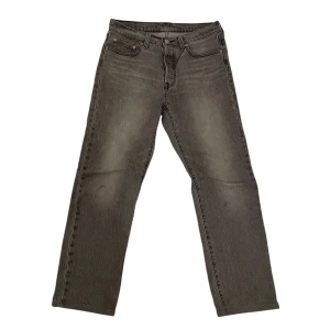 Grå Levi’s 501 jeans - Snygga grå jeans från Levi's med klassisk femficksdesign och knappgylf. Perfekta för en avslappnad stil. De har en rak passform och är tillverkade i slitstarkt denim. Storlek W28 L30 passar perfekt för dig som är runt 175.