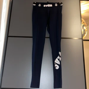 marinblå leggings från Svea - marinblå leggings från Svea med logga på midjebandet och benet. Perfekta för en casual look eller träning. Tillverkade i ett stretchigt material för bästa komfort. Dom passade mig perfekt när jag var ca 155-160. Mått kan jag lösa bara att skriva till mig så löser jag. Frakt betalar köparen, kan hämtas i Mölnlycke.