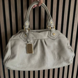 Marc Jacobs väska (stor) - Marc Jacobs classic q baby groove med guldiga detaljer. Väskan är beige. Axelremband ingår. Den är ca 40 cm bred och är i den stora modellen. Dustbag ingår. Mycket bra skick. Fler bilder finns och svarar gärna på frågor 🤍