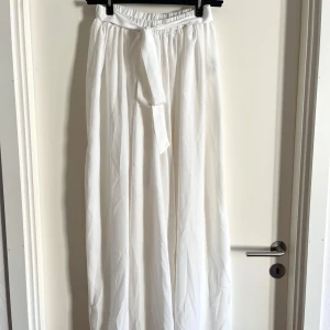 Vida byxor - Vita, vida byxor med knytband! De har en relaxed, flowy och elegant passform som passar för sommaren! De håller sig till sin storlek S. Har använts fåtal gånger. Midjan kan man själv justera då man knyter med bandet uppe till! Alla använda plagg tvättas noga innan leverans! Det är bara att skriva om du har några frågor! <3