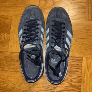 Adidas Spezial  - Snygga Adidas Spezial  sneakers i mörkblå mocka med de klassiska tre ränderna i ljusblått. Skorna har mörkblå snörning och en brun sula. Perfekta för en stilren och grischig look. Knappt använda.