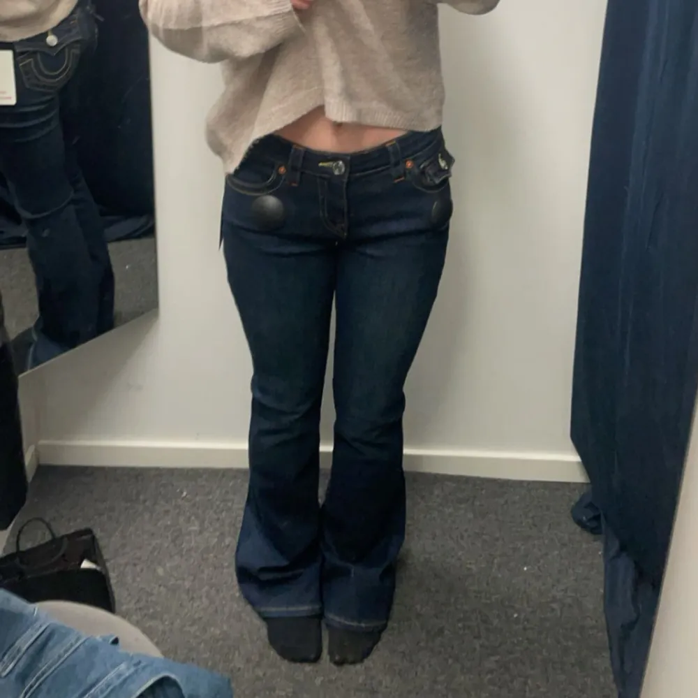 Snygga mörkblå bootcut jeans från True religion med midwaist passform. Jeansen har klassiska fem fickor och kontrastsömmar som ger en stilren look. Perfekta för en avslappnad stil.. Farkut & Housut.