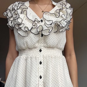 Vit prickig blus med volanger - Säljer min vita blus med svarta prickar och volanger. 💞Säljer då jag inte har användning för den!💞Tröja är stretchig så skulle säga att den passar allt från Xs-M ! Skriv för flera bilder.💞Pris kan diskuteras!💞