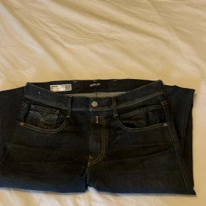 Mörkblå jeans från Replay - Snygga mörkblå jeans från Replay med klassisk femficksdesign och subtila sömdetaljer på bakfickorna. Jeansen har en knappgylf och är perfekta för en stilren look.