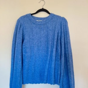 Blå stickad tröja från JDY - Säljer en snygg blå stickad tröja från JDY. Tröjan har en rund halsringning och långa ärmar med ett fint stickat mönster. Perfekt för kyligare dagar. Passar bra till jeans eller kjol för en avslappnad look.