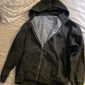 Svart hoodie från Brandy Melville - Säljer en svart hoodie från Brandy Melville med dragkedja och huva. Insidan är fodrad med mjukt grått tyg. Perfekt för en avslappnad stil. 🖤